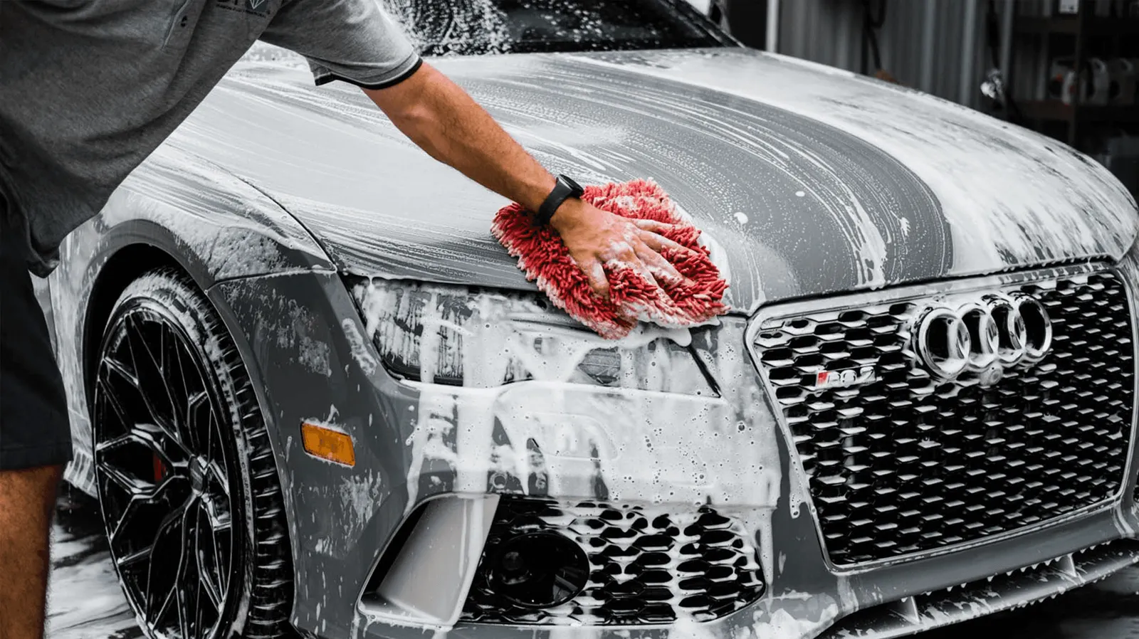 Foam-covered sedan being washed with a red mitt